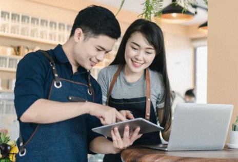 Male and female small business shopkeepers at register with tablet